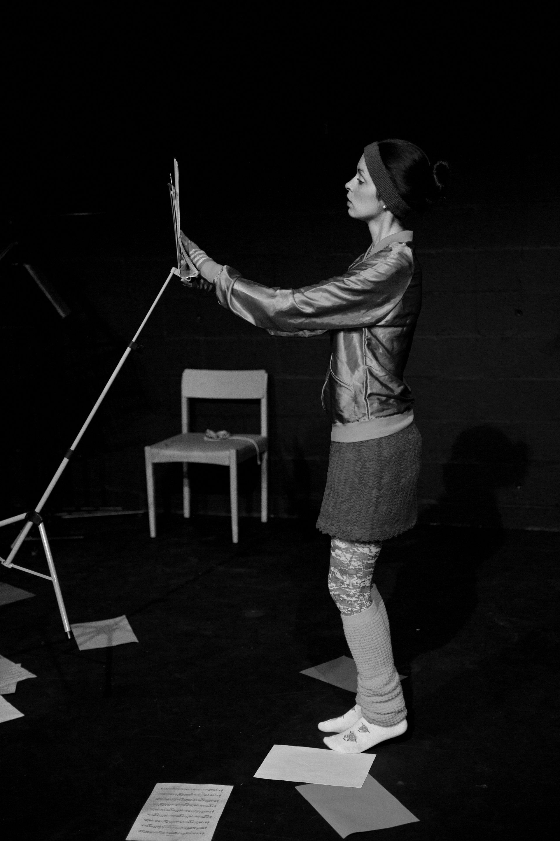 A woman is standing on a stage dancing with a music stand.
