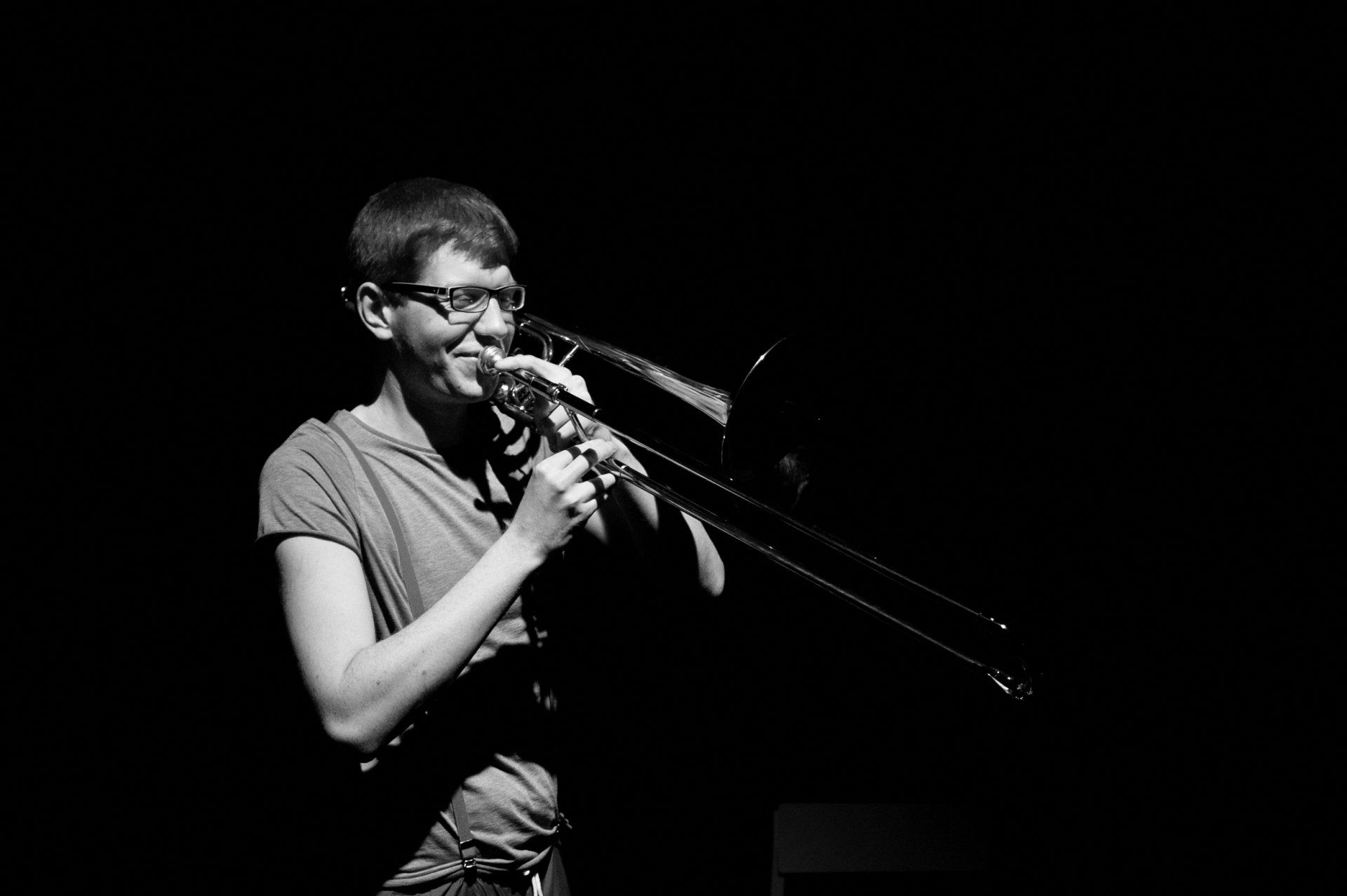 A man is playing a trombone in a black and white photo.