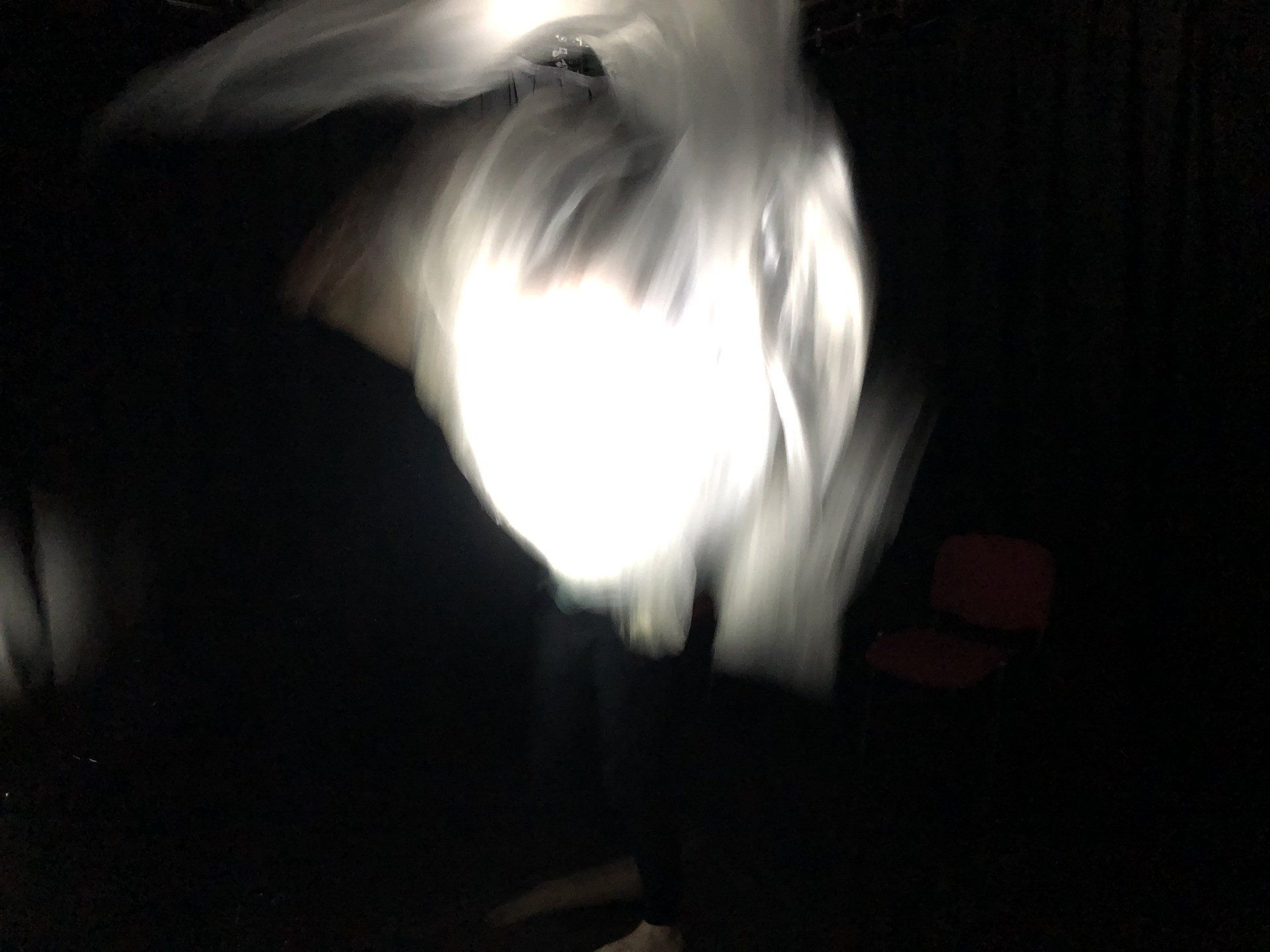 A person with a white cloth is standing in the dark