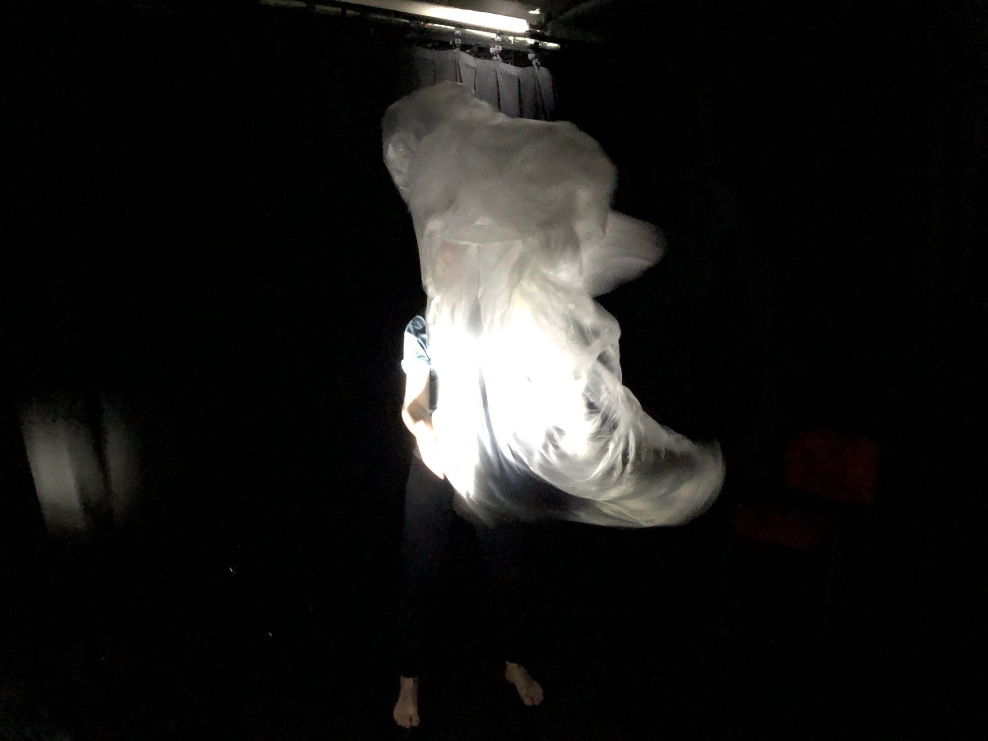 A person is standing in the dark with a light shining on them.