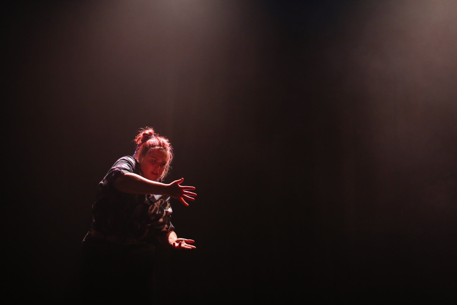 A woman is dancing on a stage in a dark room.