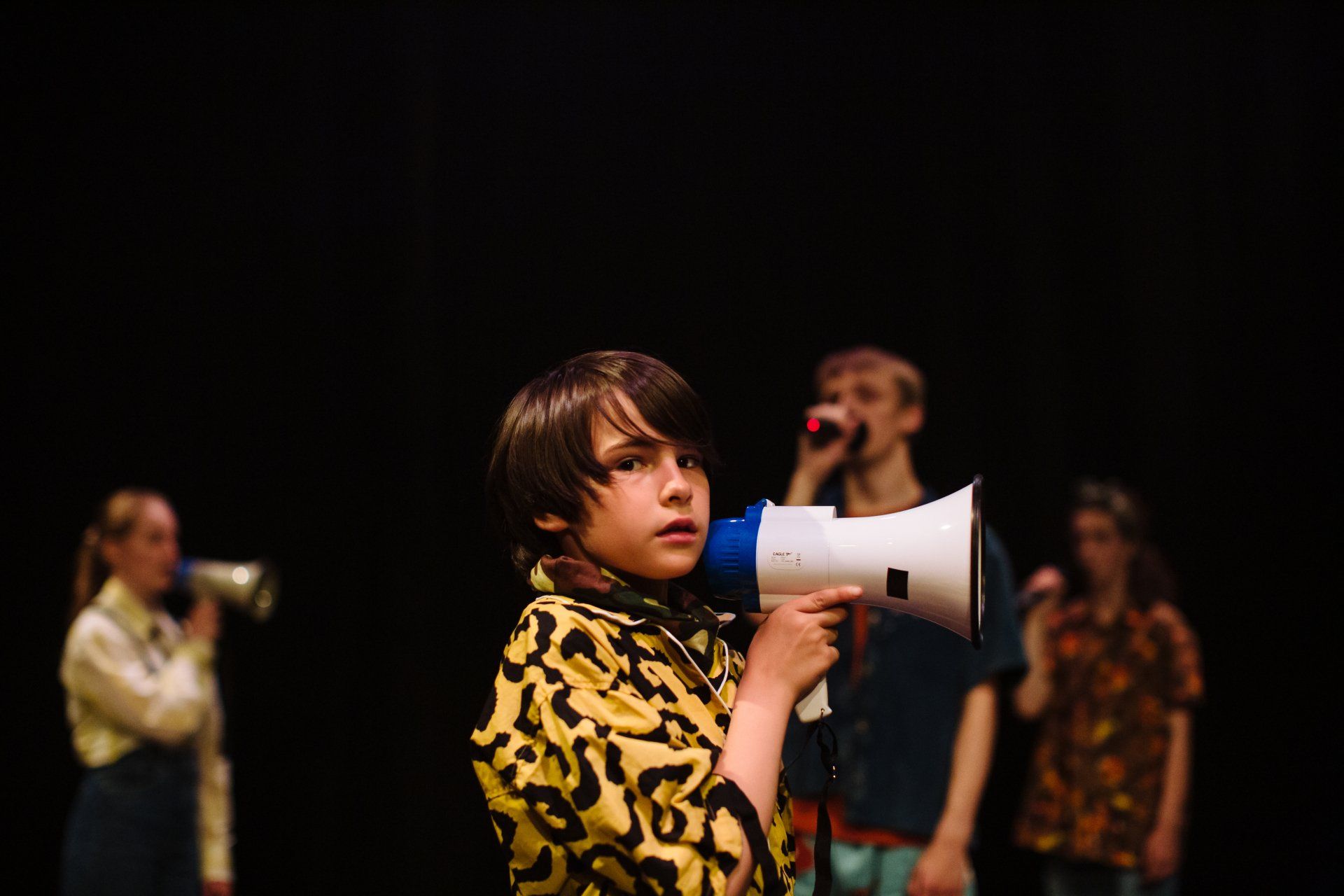 A young boy is holding a megaphone in a dark room.