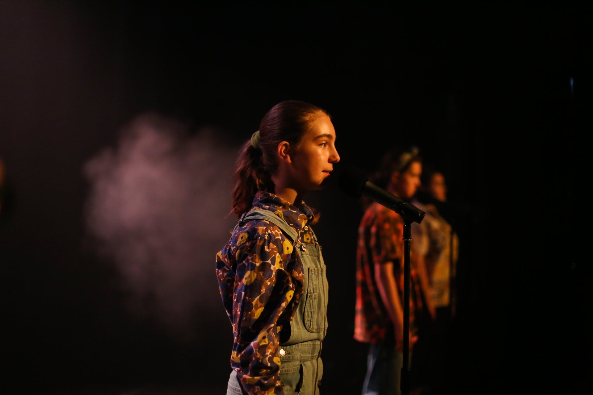 A group of people are standing on a stage in a dark room.