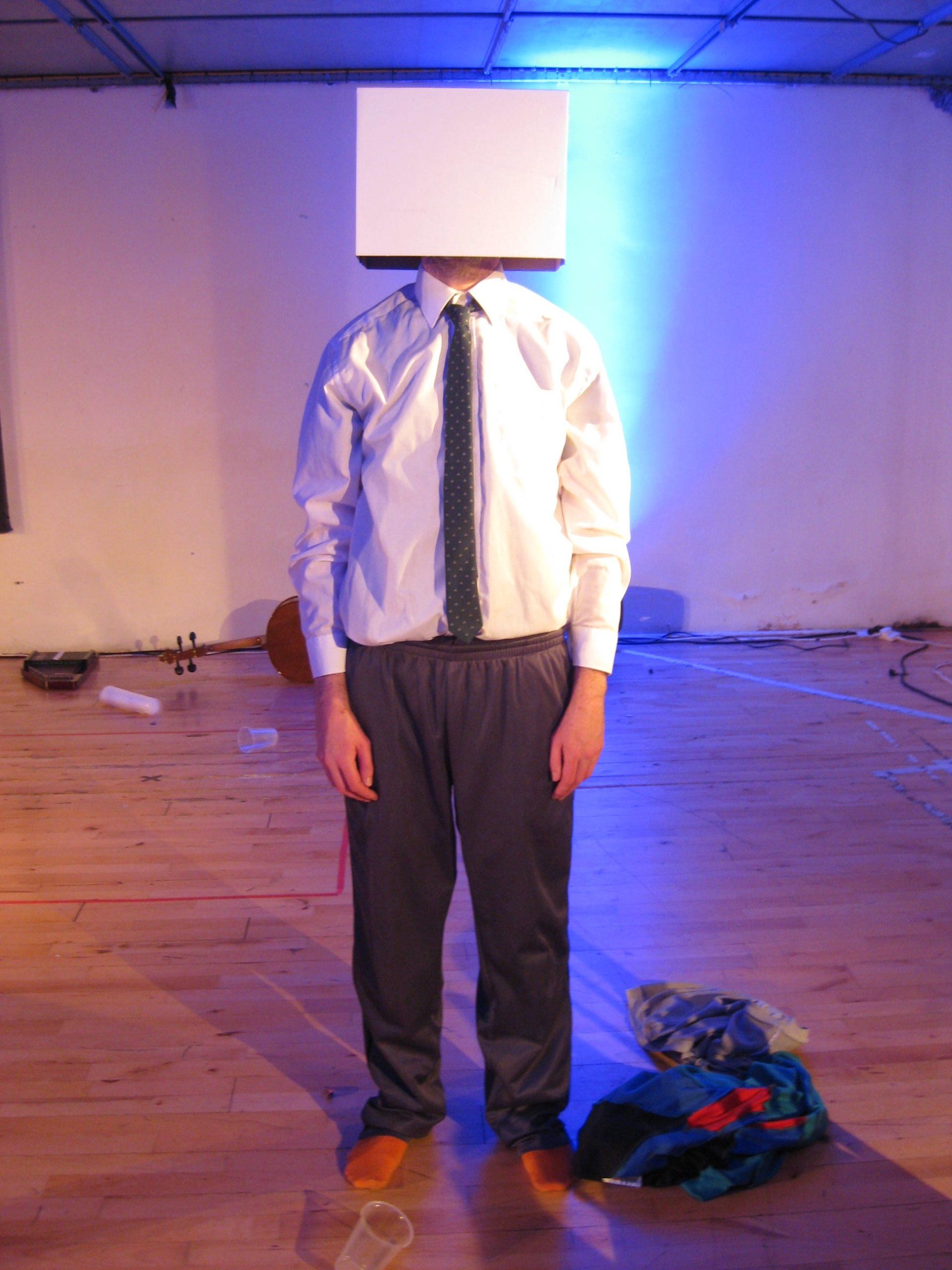 A man in a white shirt and tie has a box on his head