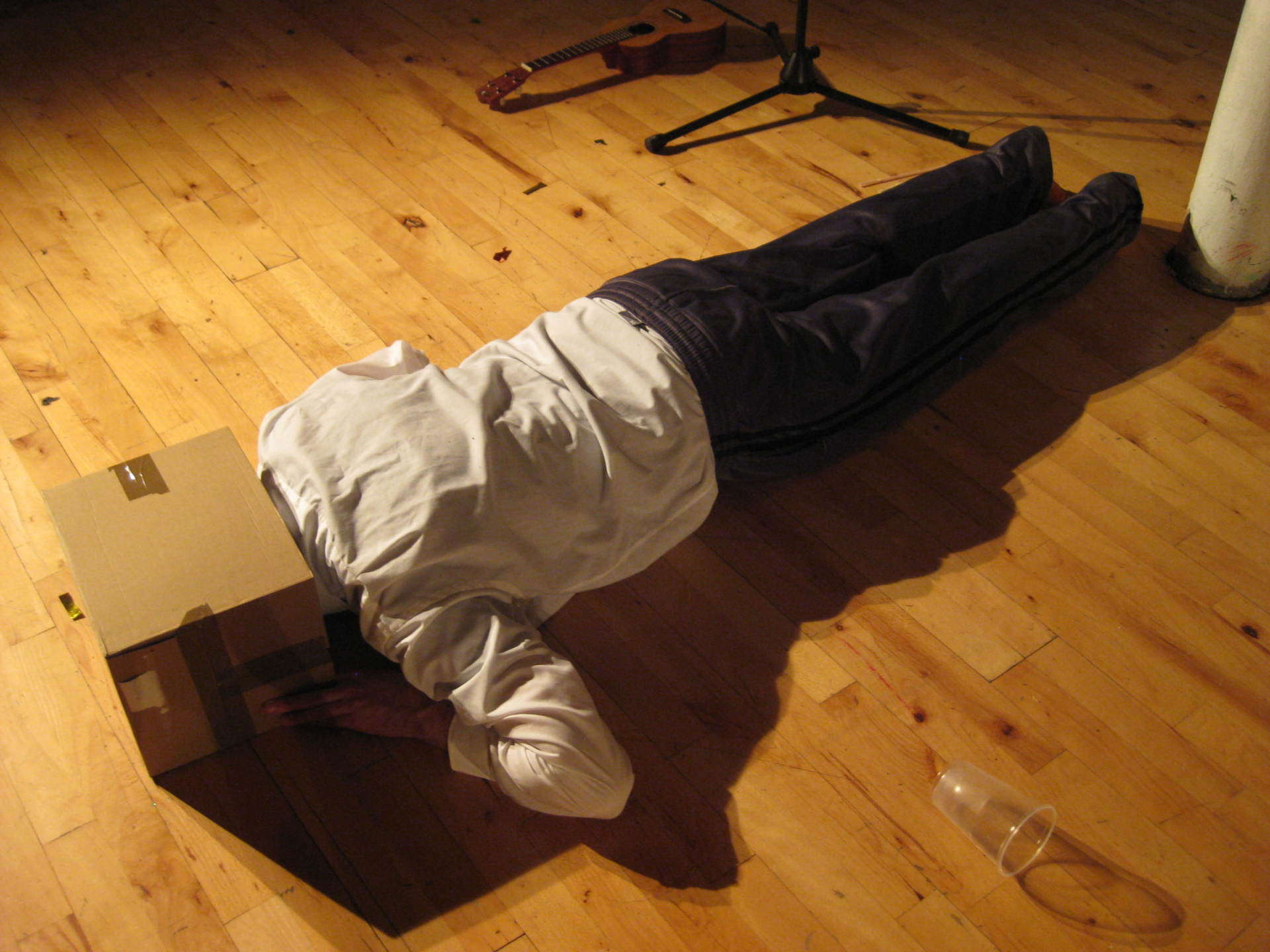 A person laying on the floor with a cardboard box on their head