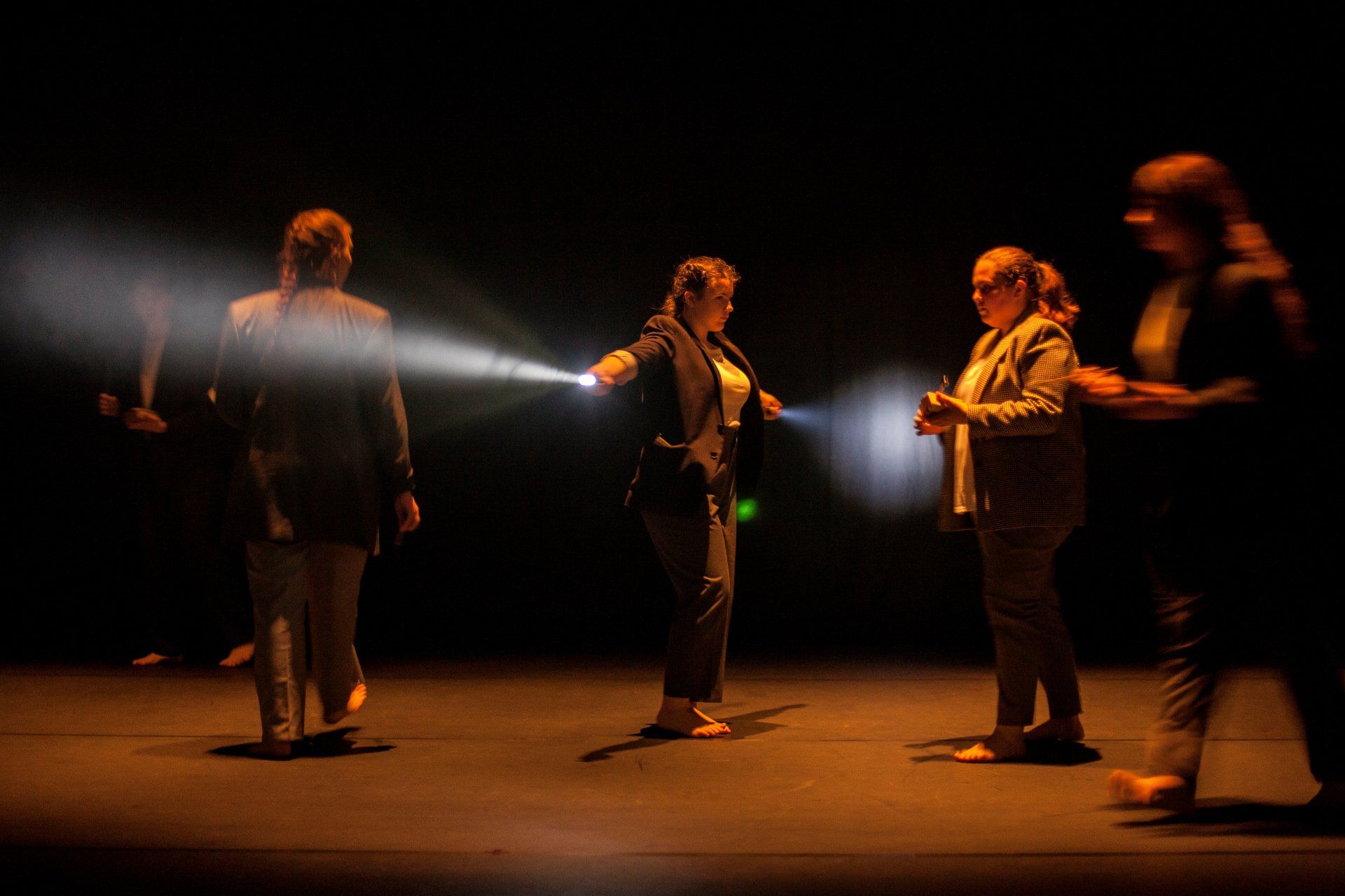 A group of people are standing on a stage holding flashlights.