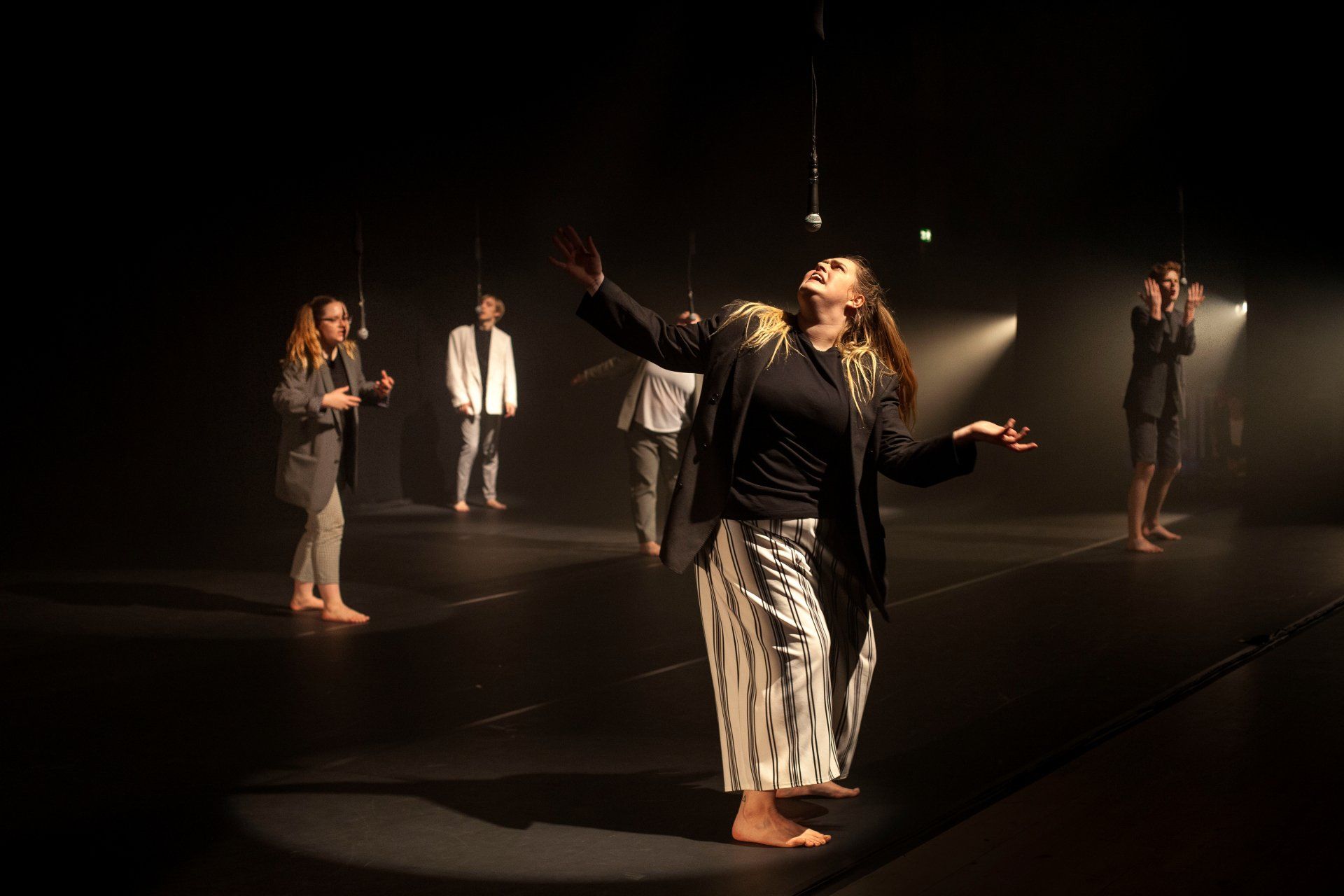 A group of people are dancing on a stage in a dark room.