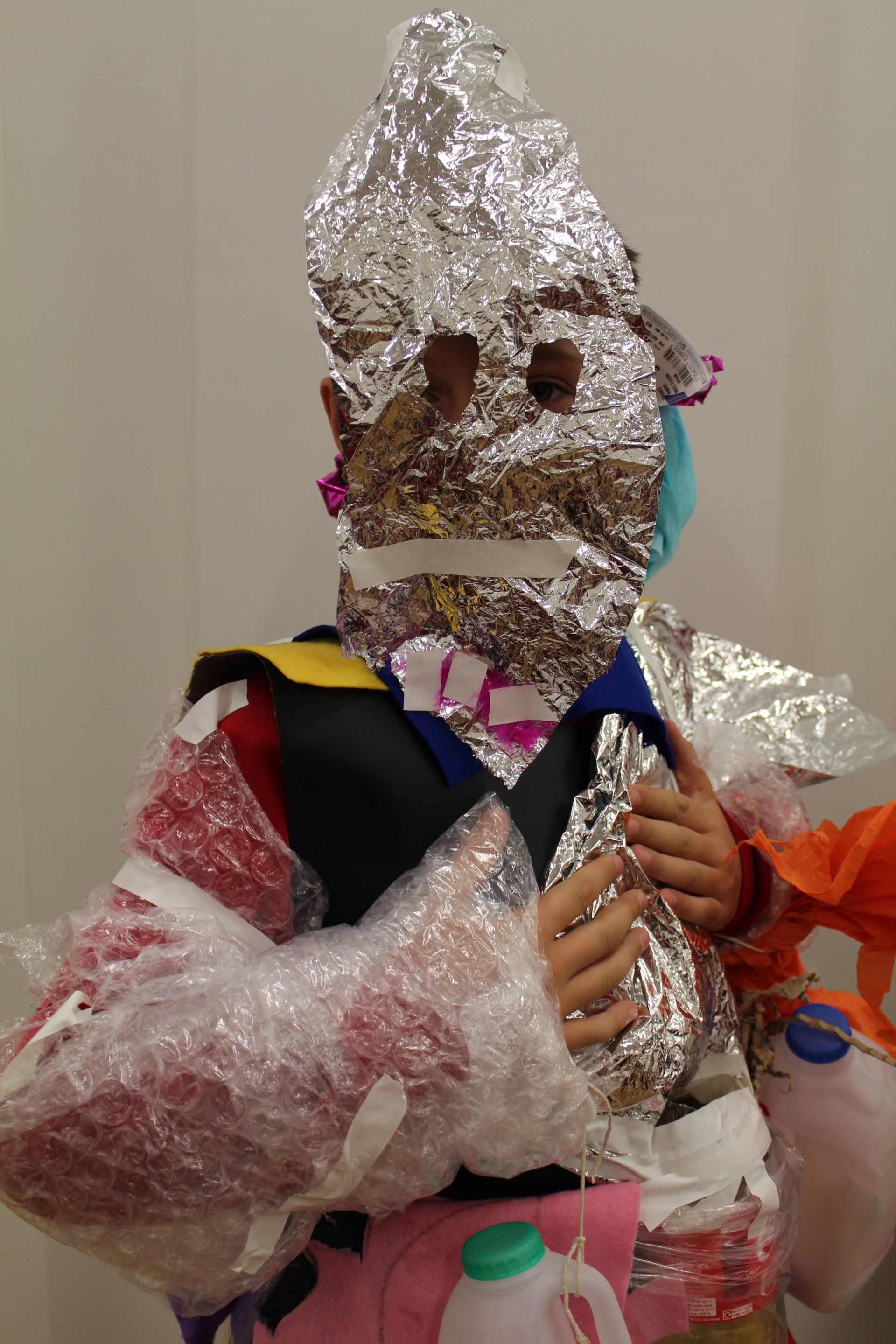 A child is wrapped in a costume made from aluminium foil and plastic wrap