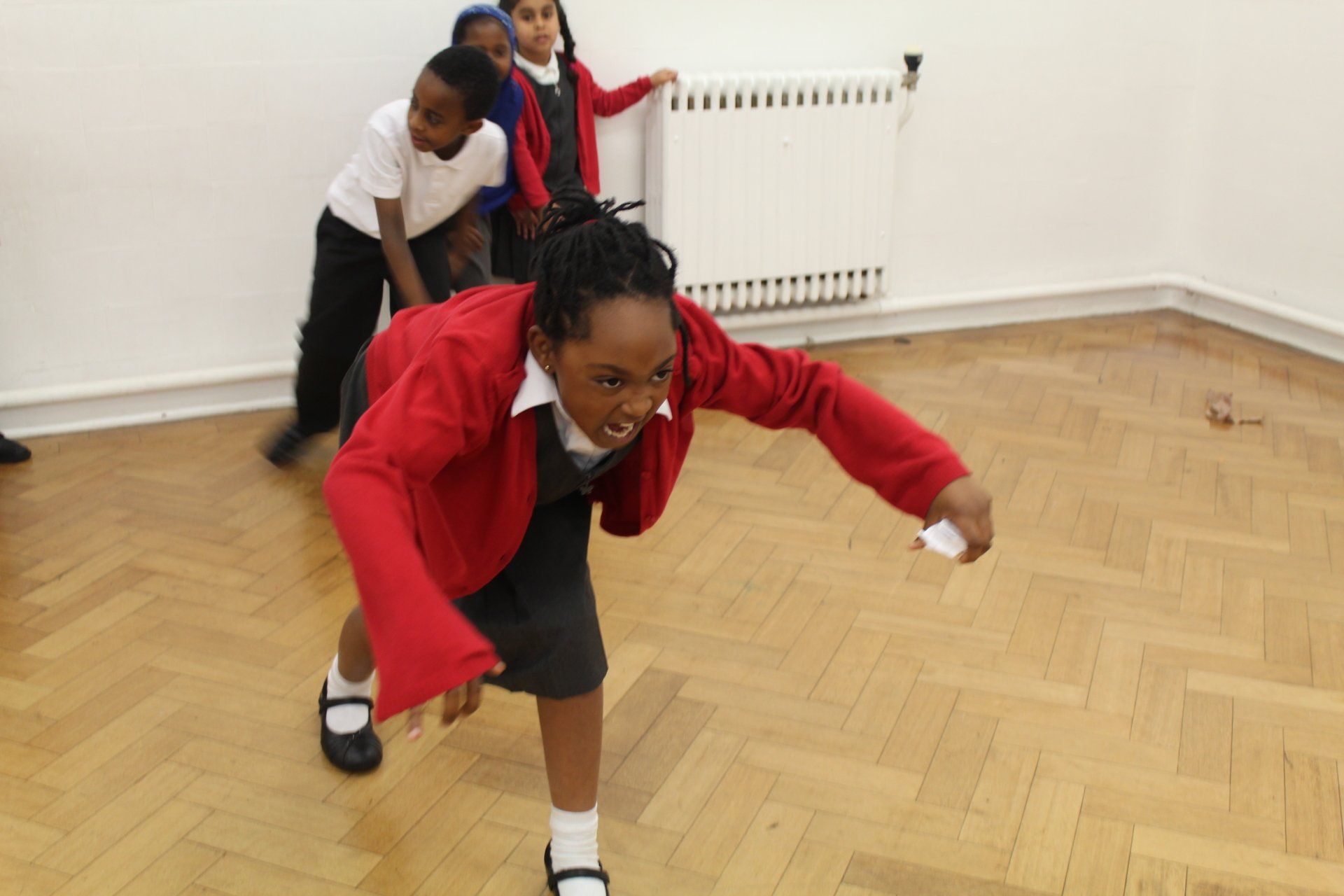 A group of children are playing a game on a wooden floor.