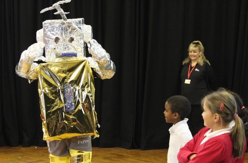 A group of children are standing around a someone in a robot costume