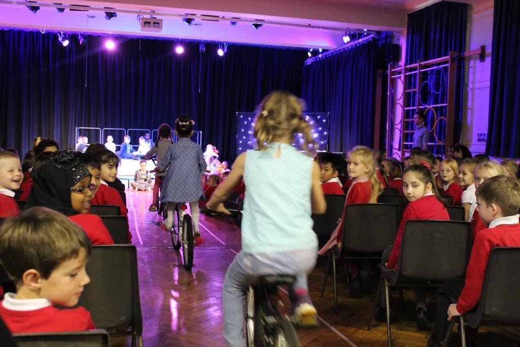 A girl is riding a bike in front of a crowd of children
