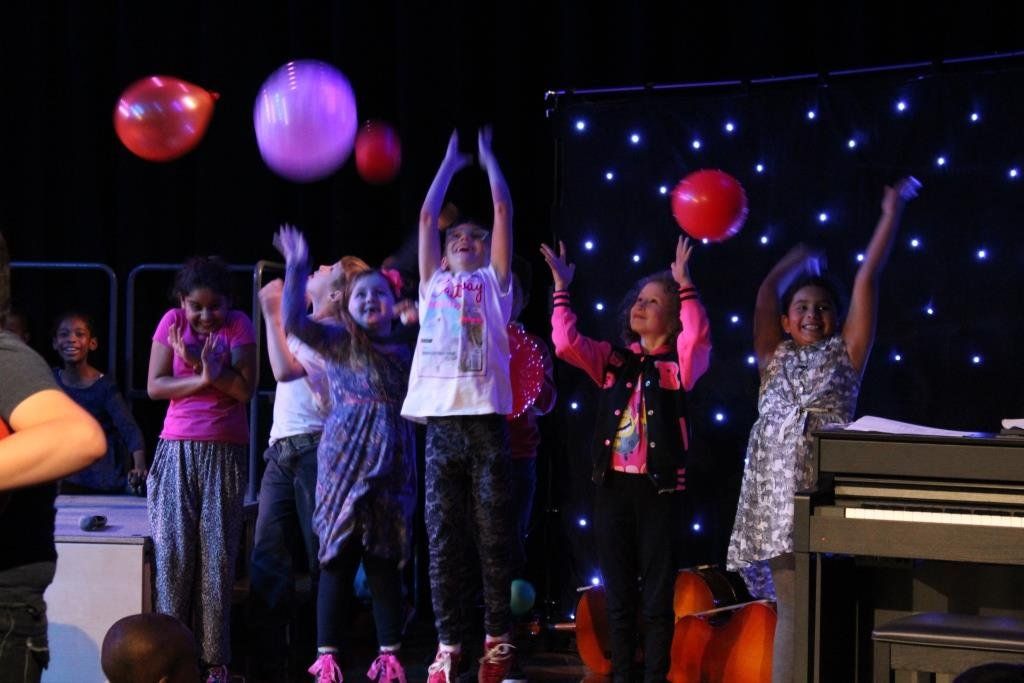 A group of children are playing with balloons on a stage.