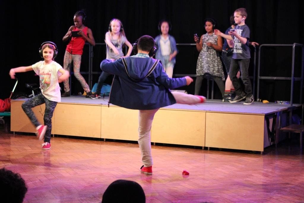 A group of children are dancing on a stage.