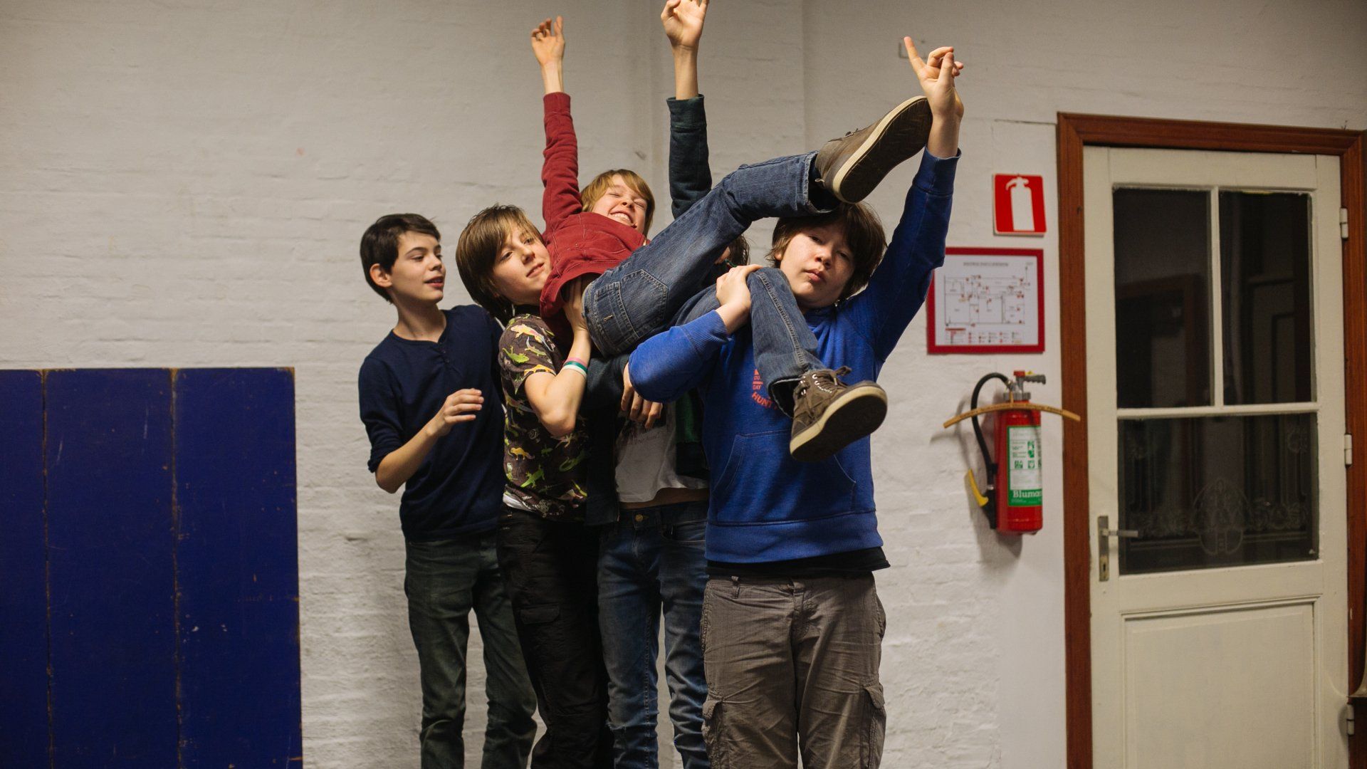 A group of children are posing for a picture with a fire extinguisher in the background.