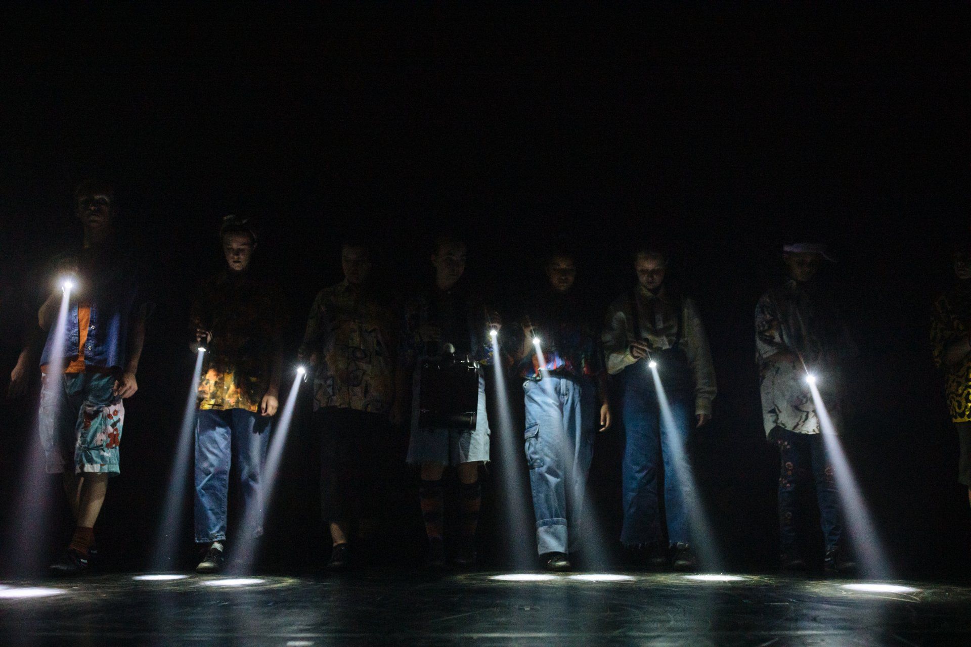 A group of people are standing in the dark holding flashlights.