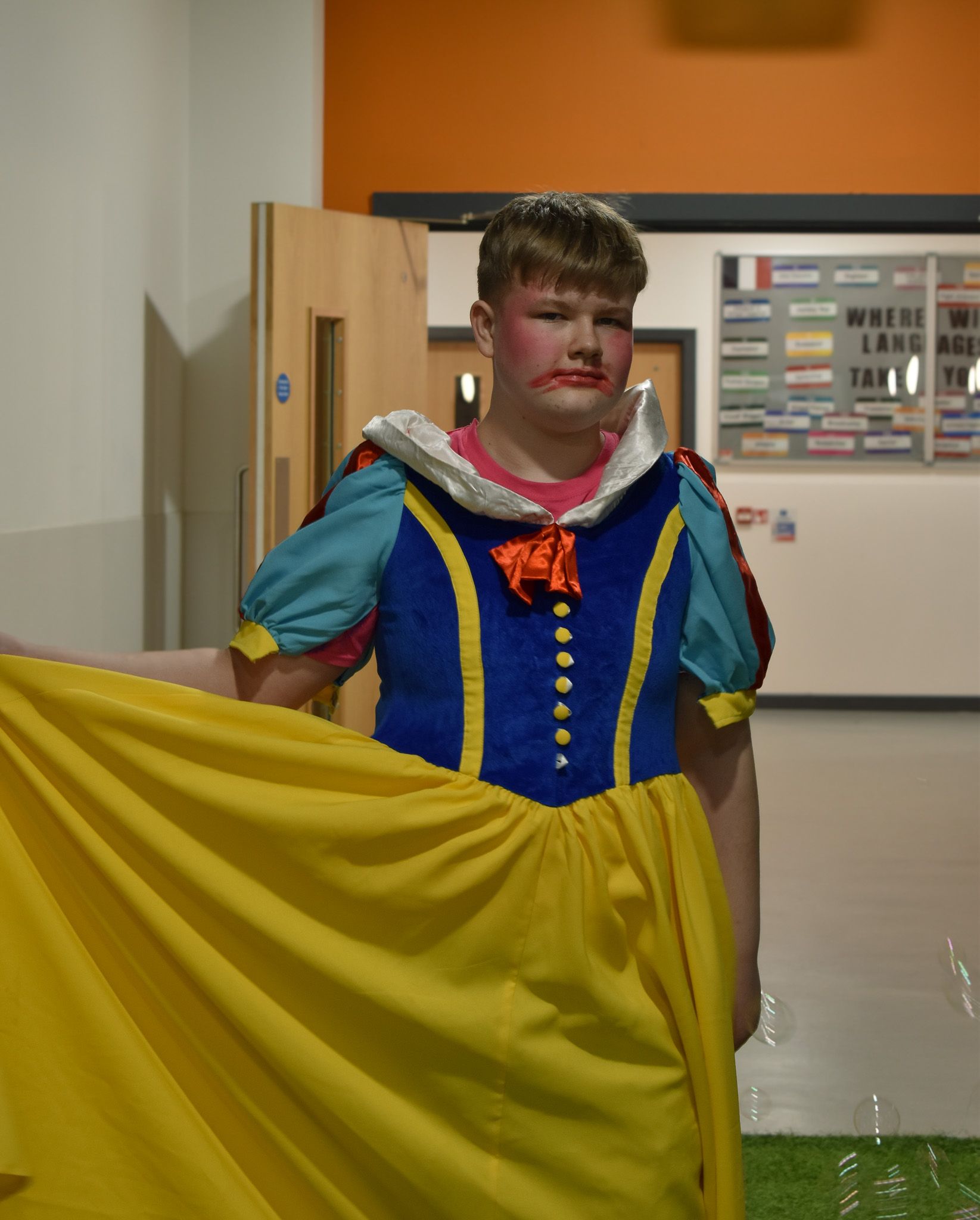 A boy dressed as snow white is holding a yellow skirt