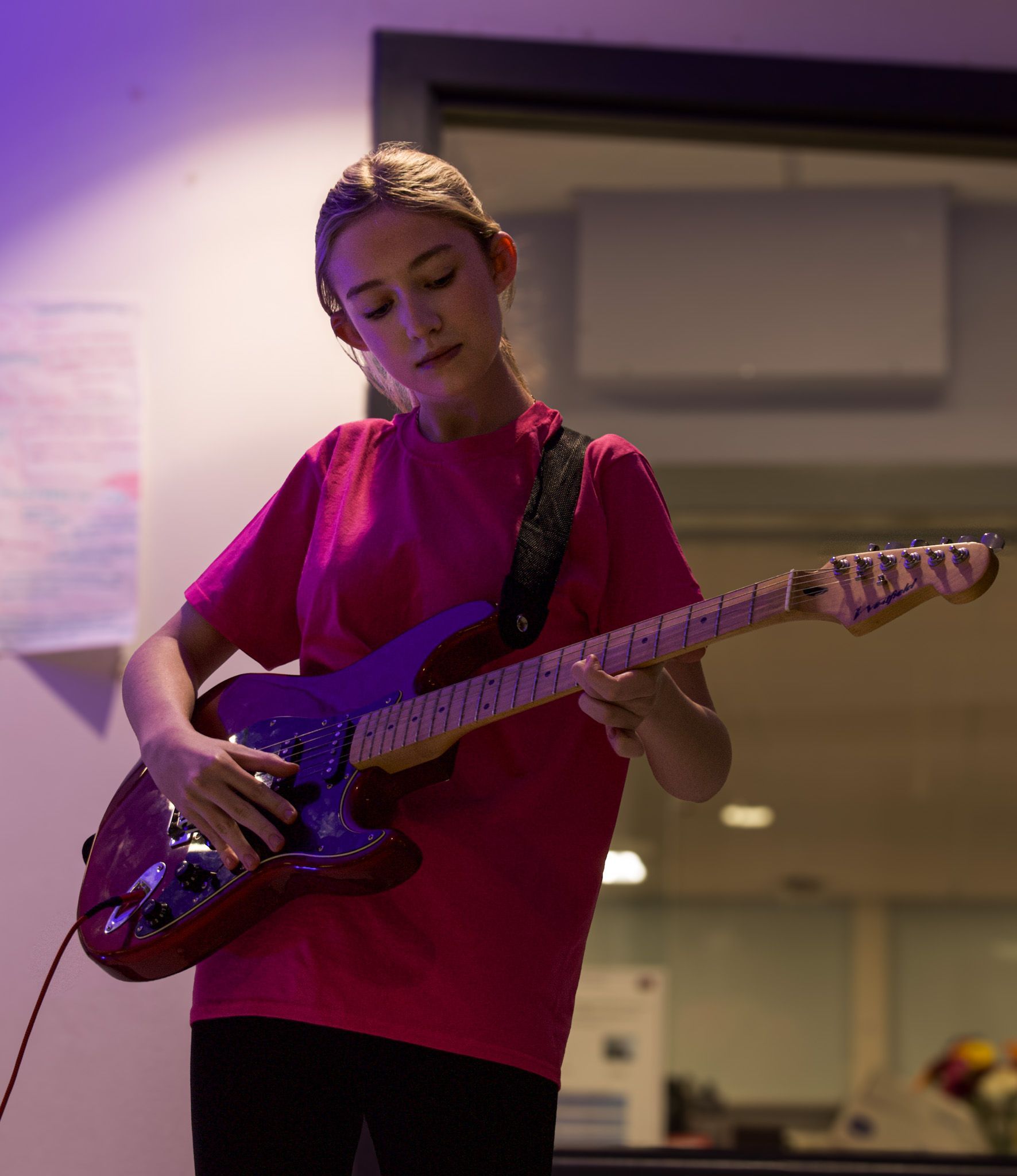 A girl in a pink shirt is playing a guitar