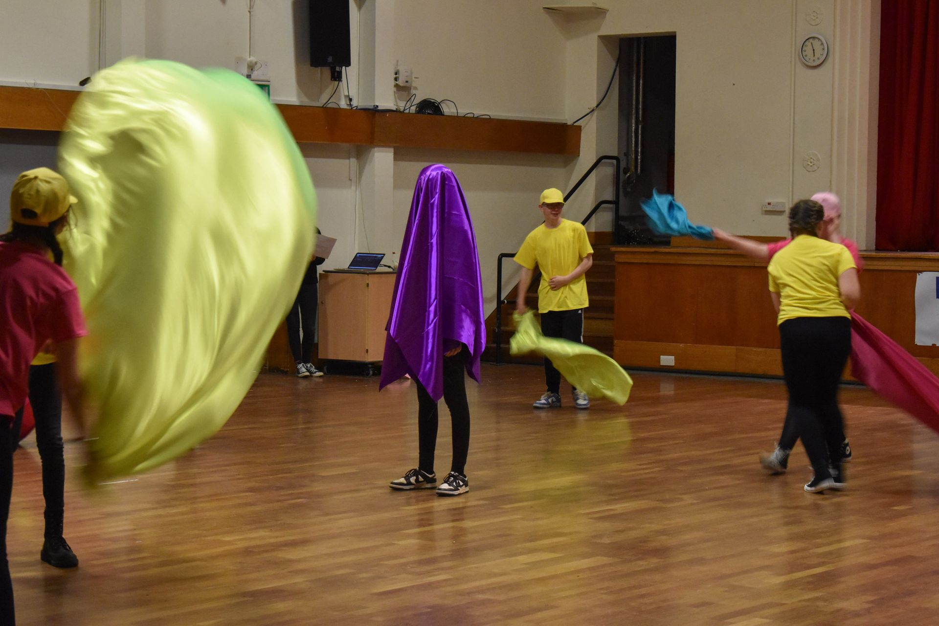 A group of people are dancing in a room while holding flags.