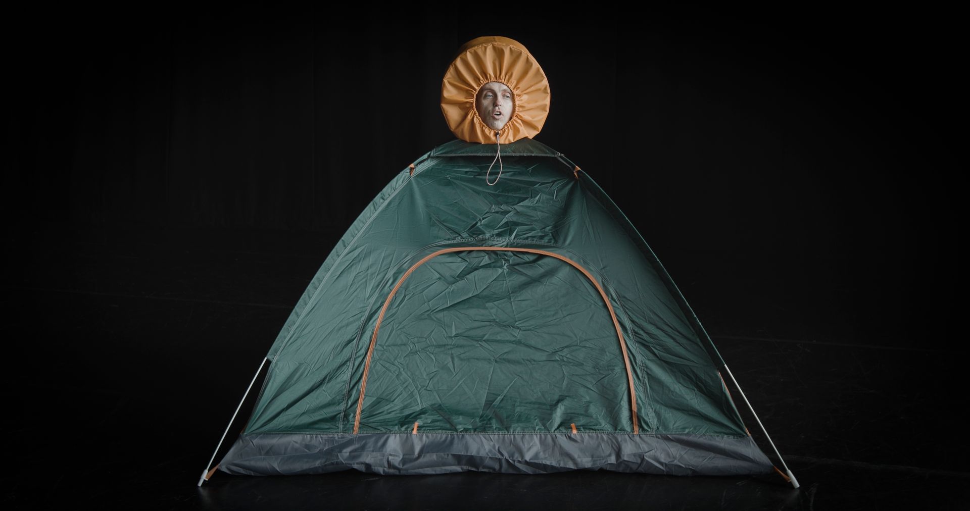 A green tent with a yellow hat on top of it on a black background.