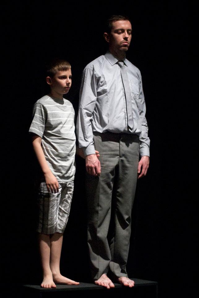 A man and a boy are standing next to each other on a stage.