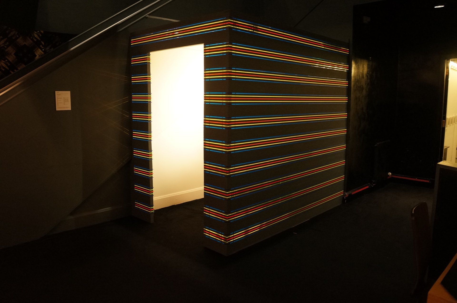 A dark room with a striped wall and a door