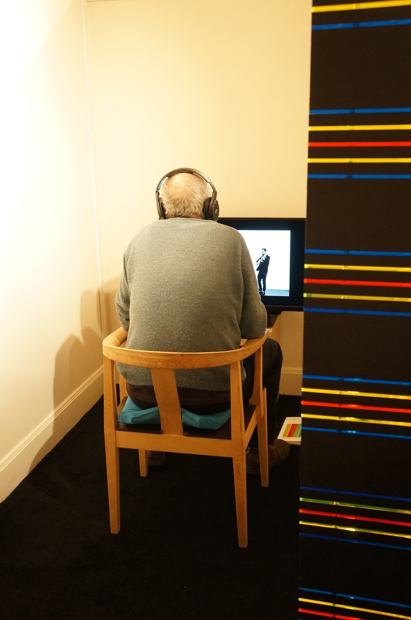 A man wearing headphones sits in a chair in front of a television