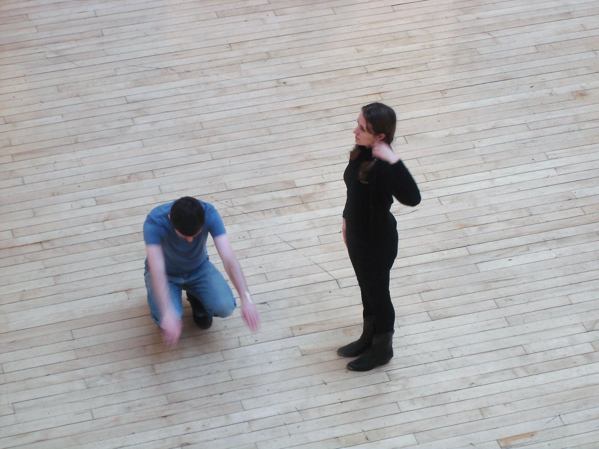 A man and a woman are standing on a wooden floor