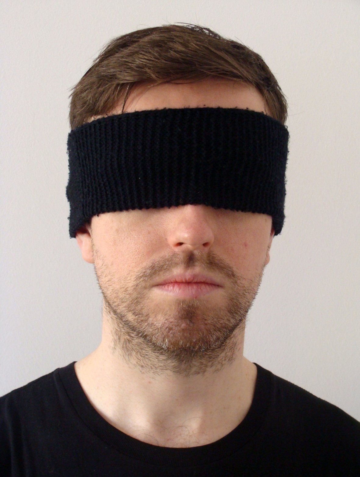 A man wearing a black headband covering his eyes