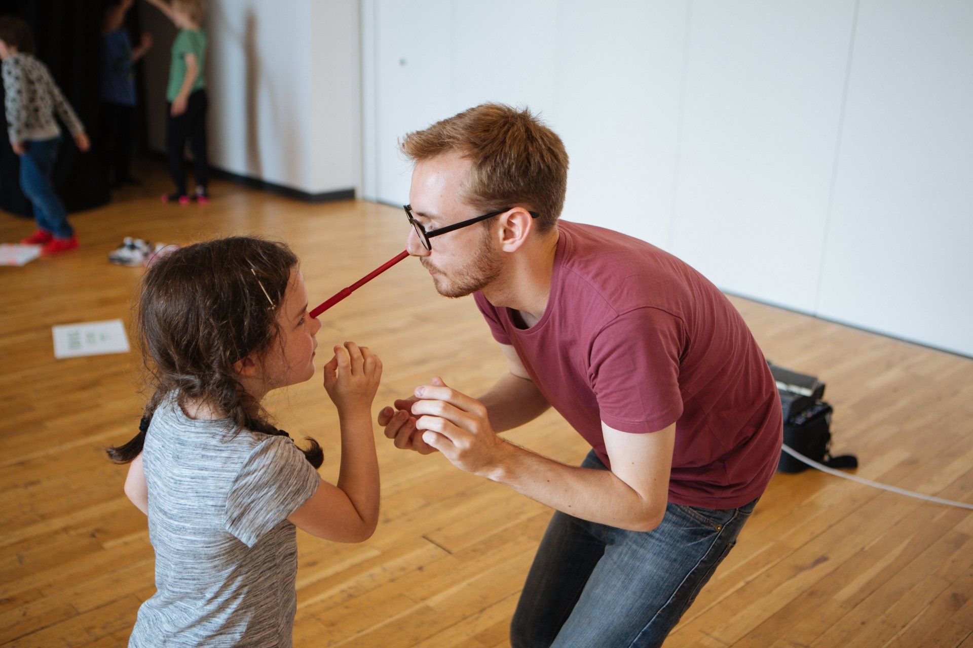 A man and a little girl are playing with a red pencil.