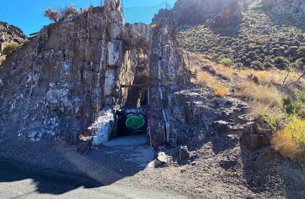 A tunnel in the middle of a mountain with graffiti on the side of it.