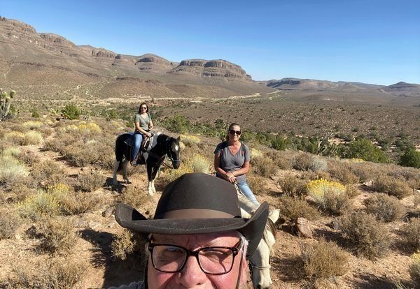 A man and a woman are riding horses in the desert.