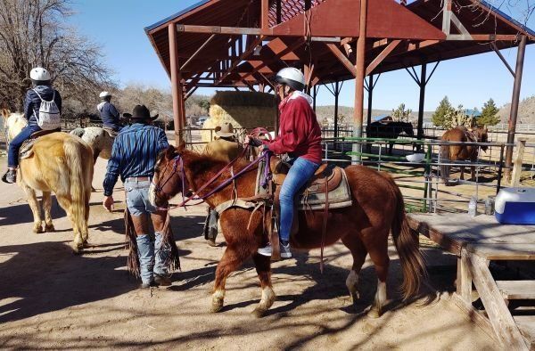A group of people riding horses in a stable