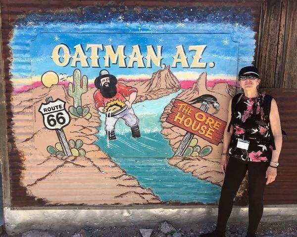 A woman is standing in front of a mural that says oatman az.