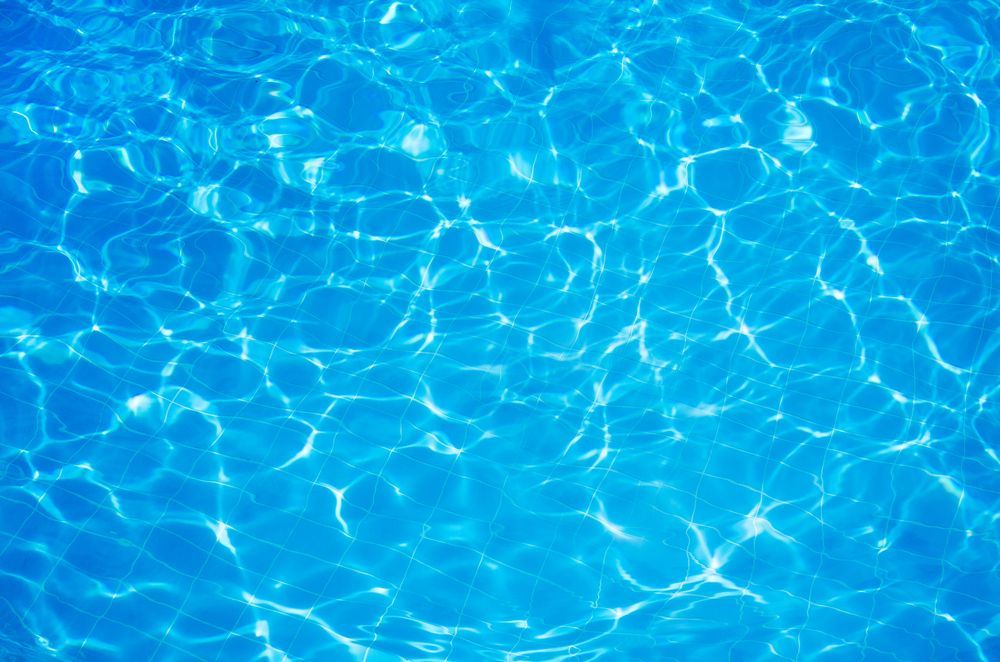 The sun is reflected in the water of a swimming pool.