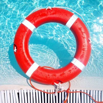 A red life preserver is floating in a swimming pool