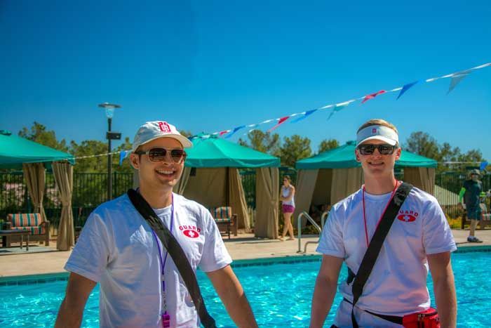Two lifeguards are standing next to a swimming pool.