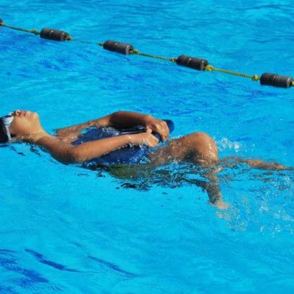 A person is floating on their back in a swimming pool.
