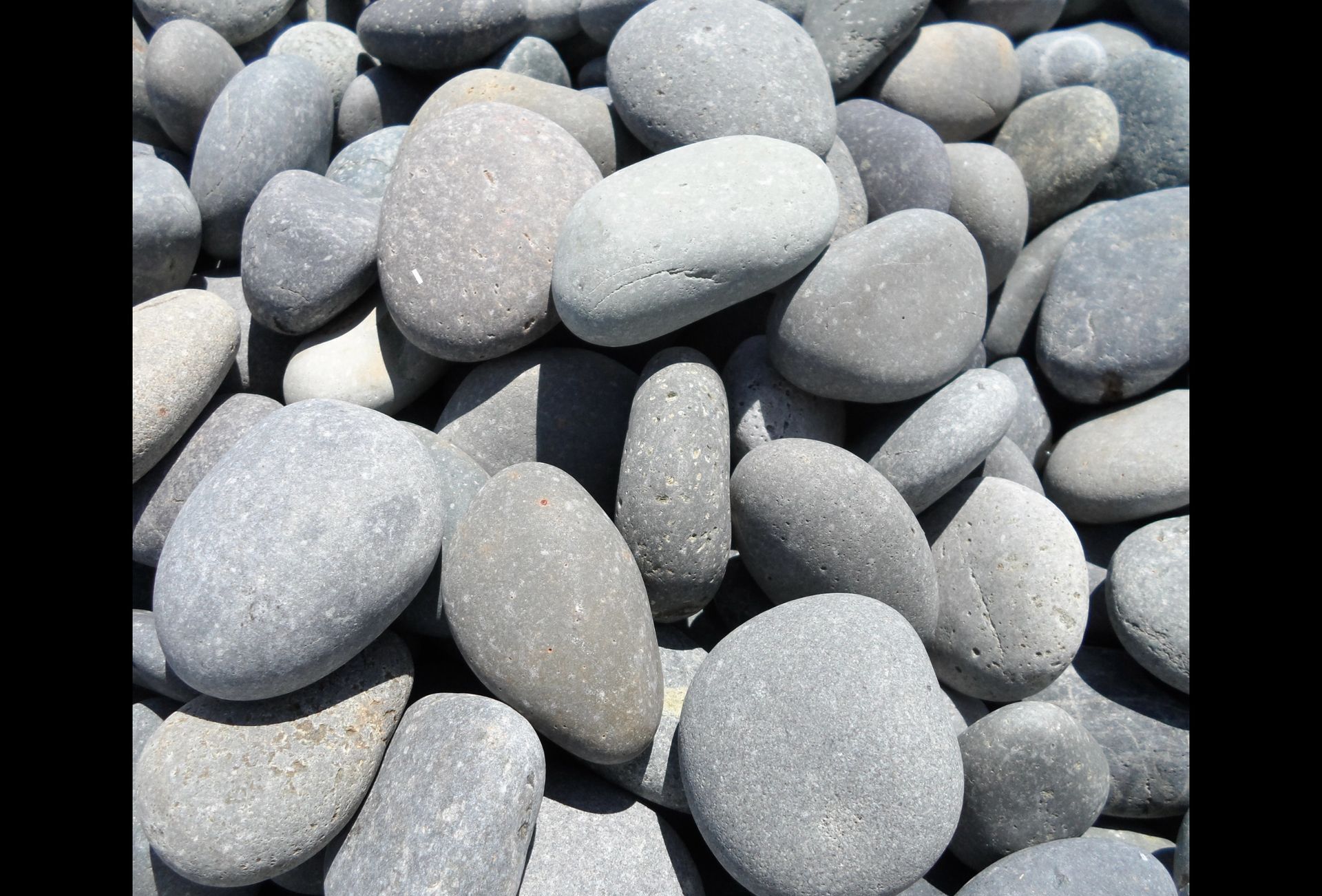 A close-up pile of smooth, rounded, gray stones of various sizes and shapes.
