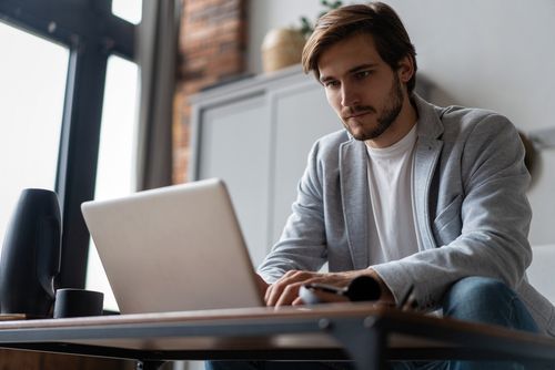 Person working on a laptop at a desk in a modern office, with a focused expression.
