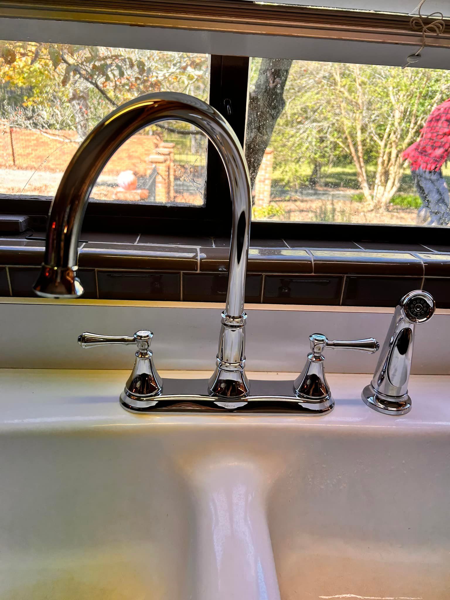 A kitchen sink with a faucet and a window in the background