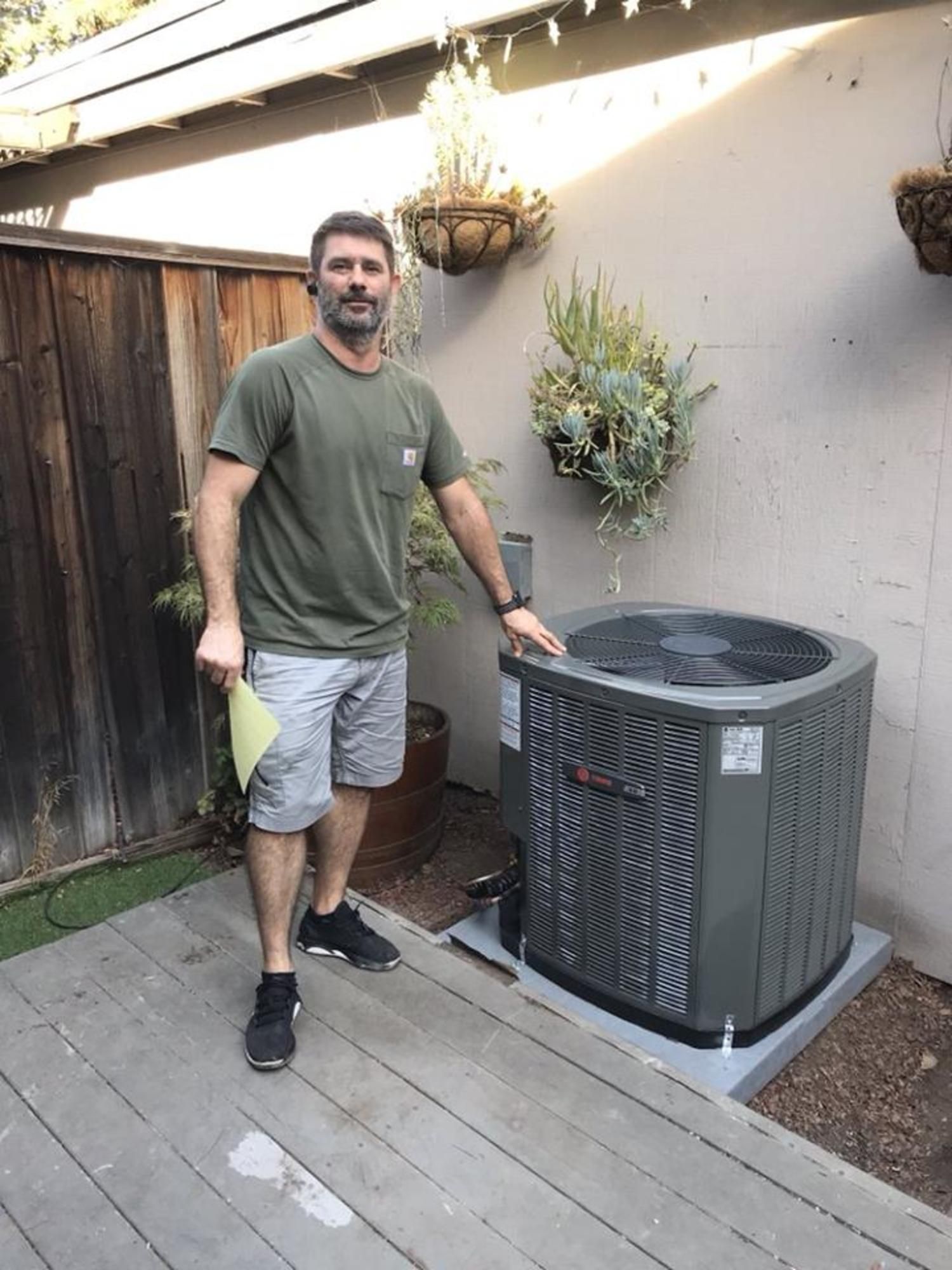 a man is standing next to an air conditioner on a deck .