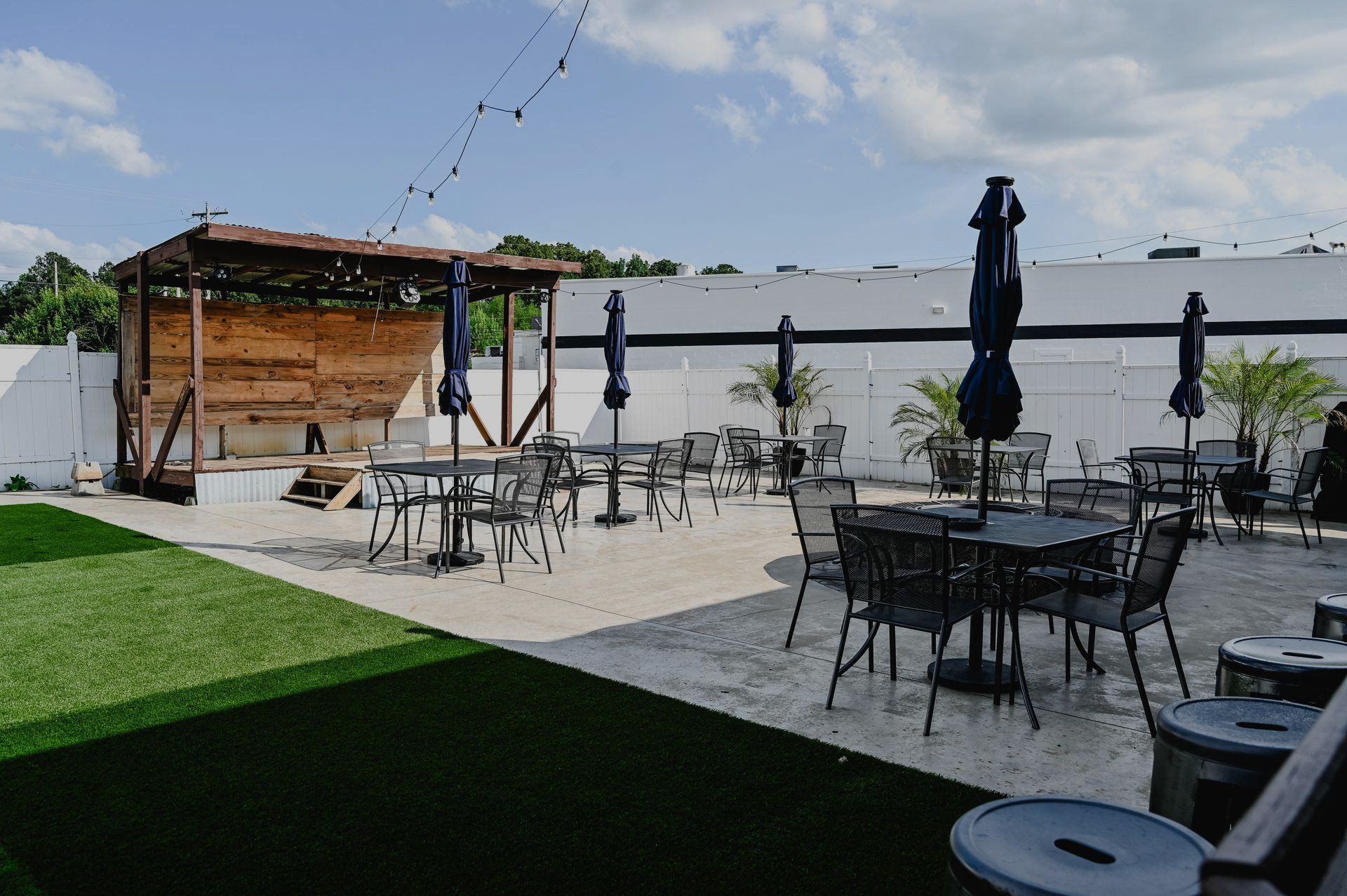 A patio with tables and chairs and umbrellas in front of a building.