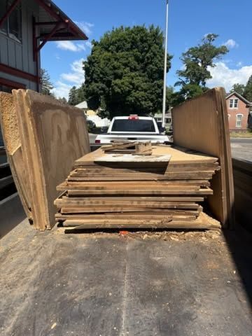 Truck bed loaded with stacked plywood and boards in a driveway outdoors