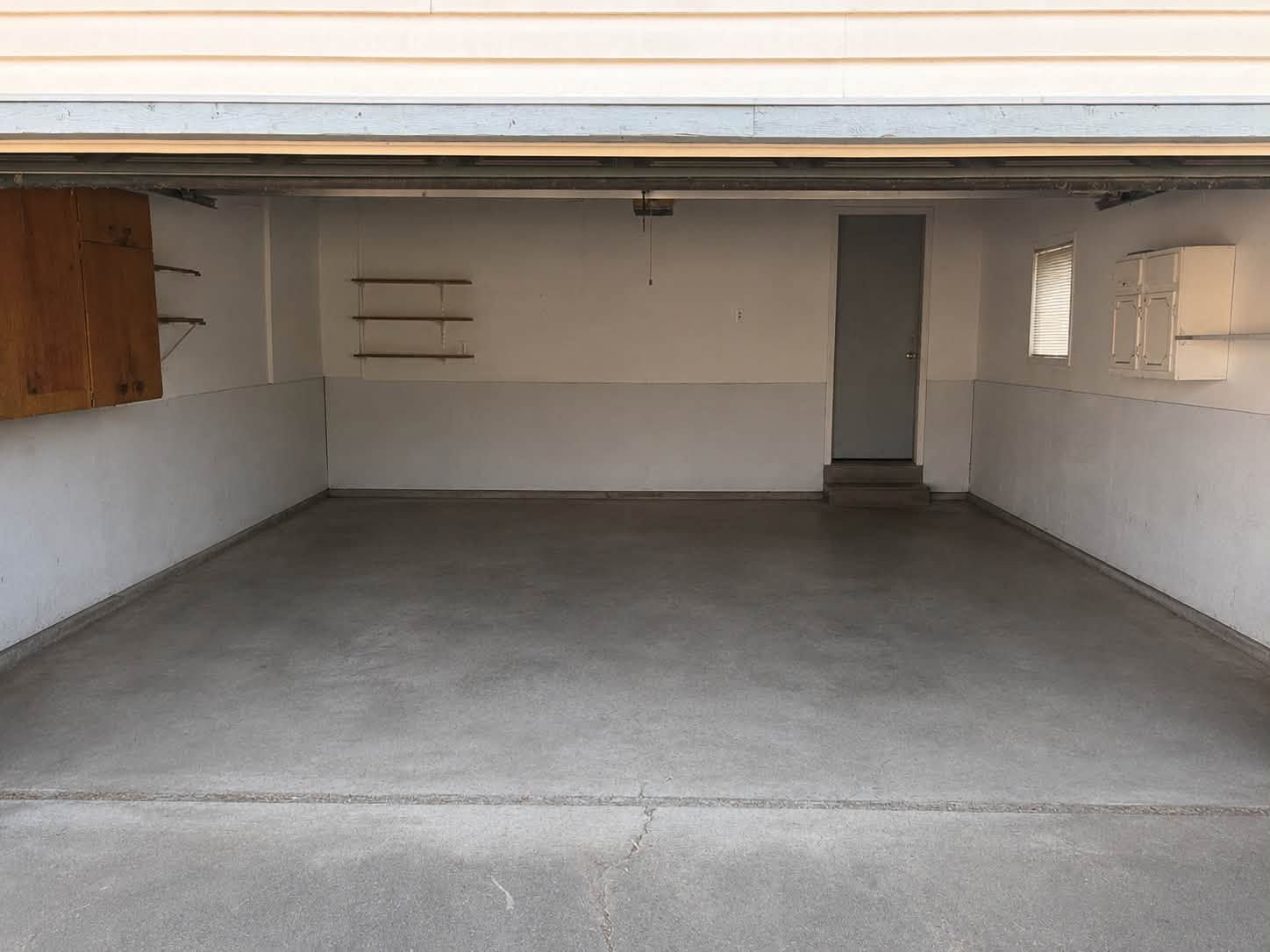 Empty garage interior with concrete floor, white walls, and an overhead door opening.