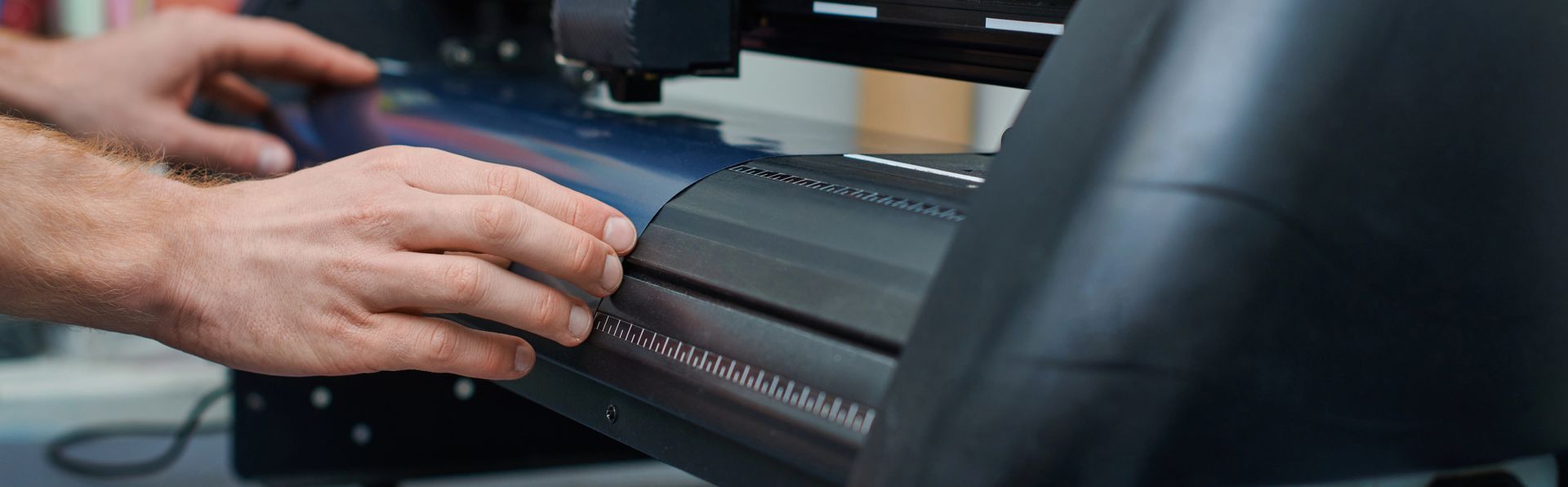 Mani che regolano un dispositivo nero su una scrivania vicino a un monitor del computer.