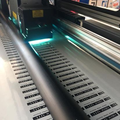 Stampante di grande formato che stampa etichette su un rotolo di carta con luce ciano all'interno della macchina