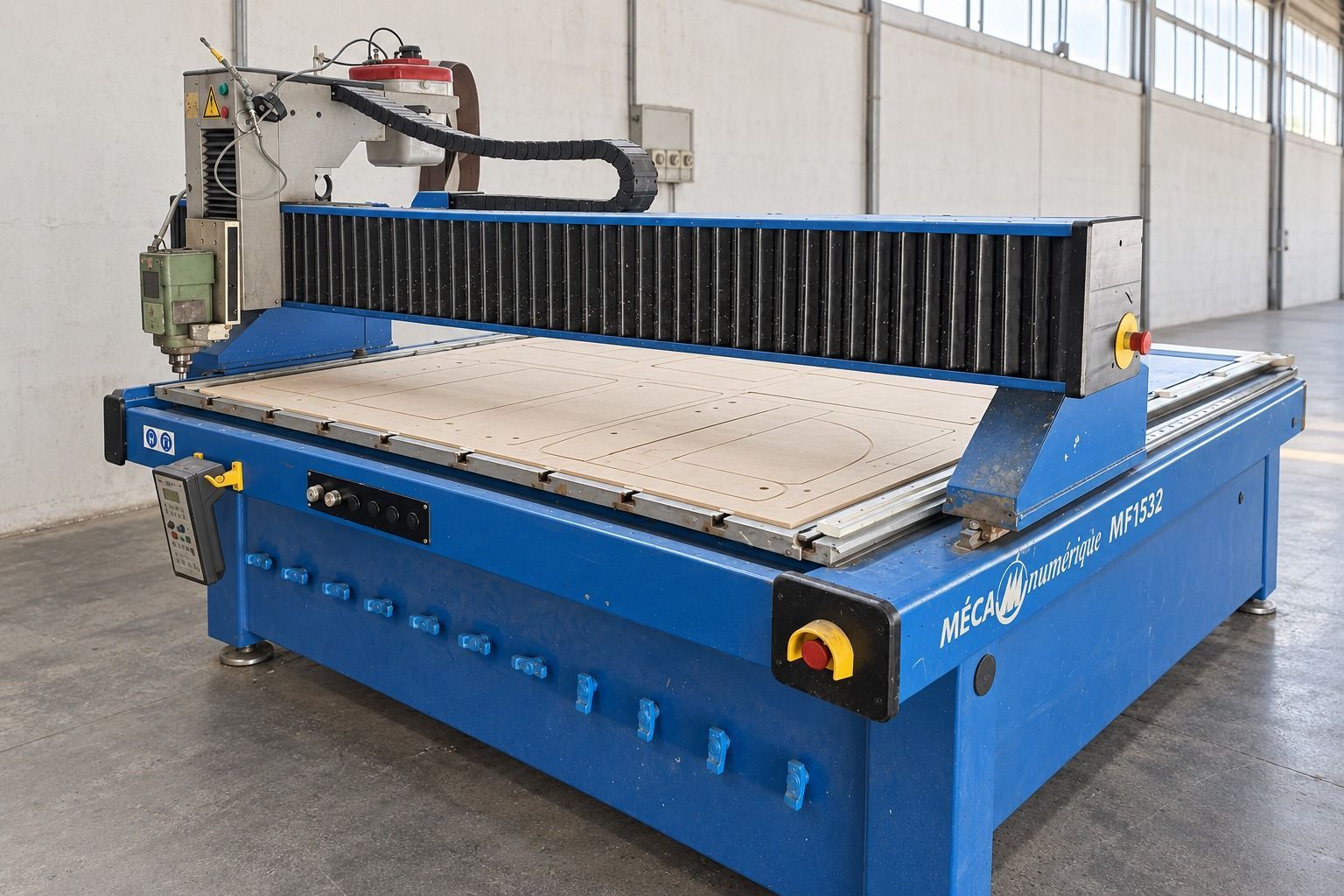 Fresatrice CNC blu in un'officina industriale, con un ampio piano di lavoro e testa portautensili verticale.