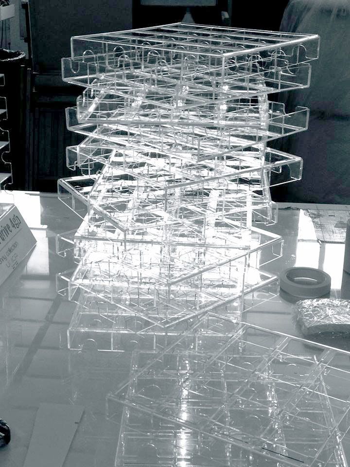 Scultura astratta in acrilico trasparente su un tavolo in uno spazio simile a una galleria.