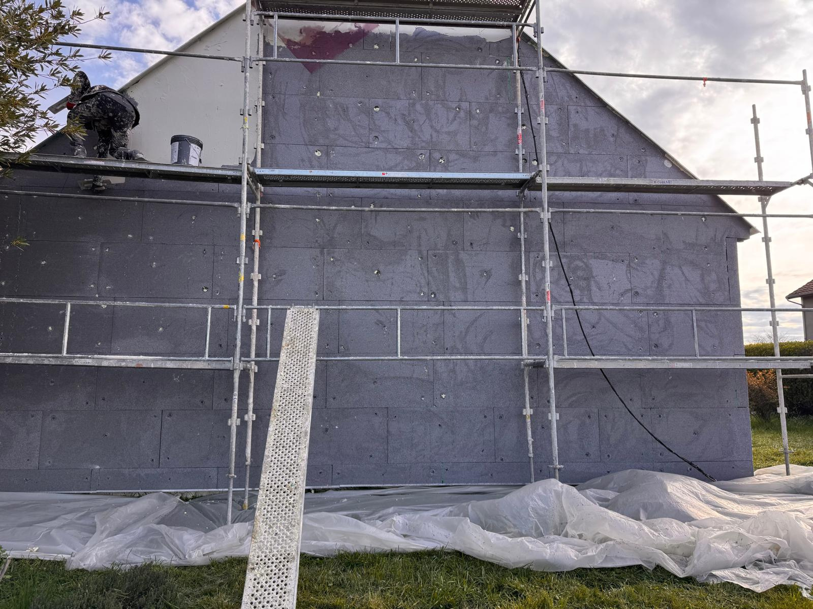 L'extérieur de la maison est recouvert d'échafaudages gris pendant les travaux de rénovation,