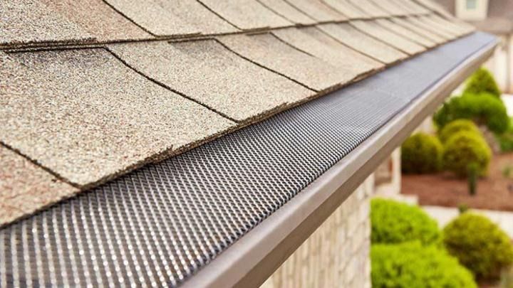 A close up of a gutter with a roof in the background